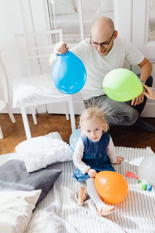 Free Father and child enjoy playful moments with colorful balloons indoors, capturing joyful expressions. Stock Photo