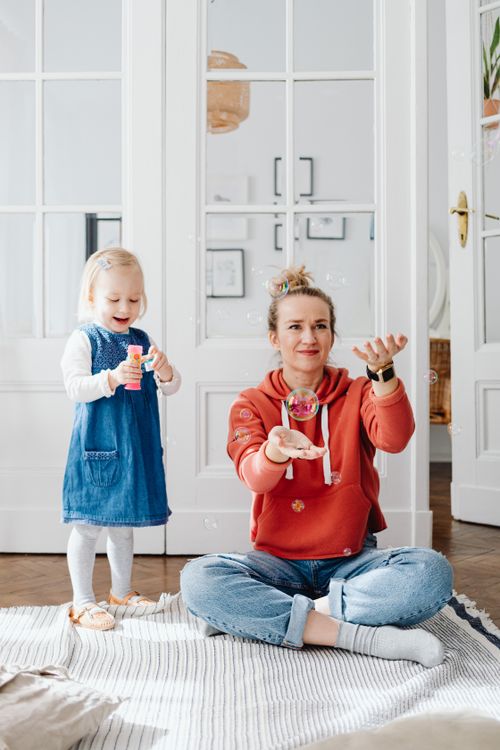 Free A joyful mother and daughter playing and blowing bubbles together at home. Stock Photo