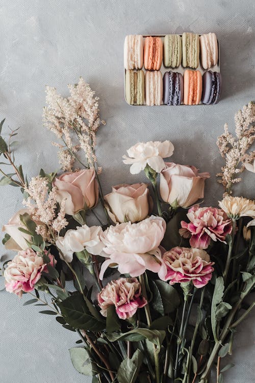 Box with sweet macaroons near tender fragrant bouquet