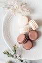 Overhead composition of delicious fresh macaroons of chocolate and vanilla flavors served on ceramic plate on plate