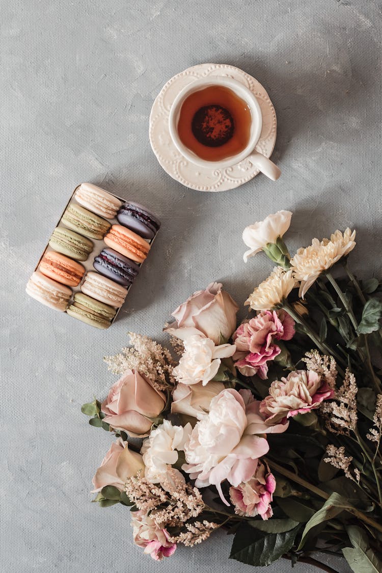 Box With Macaroons Near Tea Cup And Bouquet Of Flowers