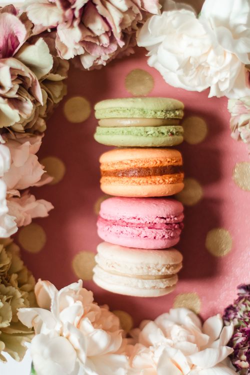 Free Vibrant macarons framed by blooming flowers on a pink background. Stock Photo