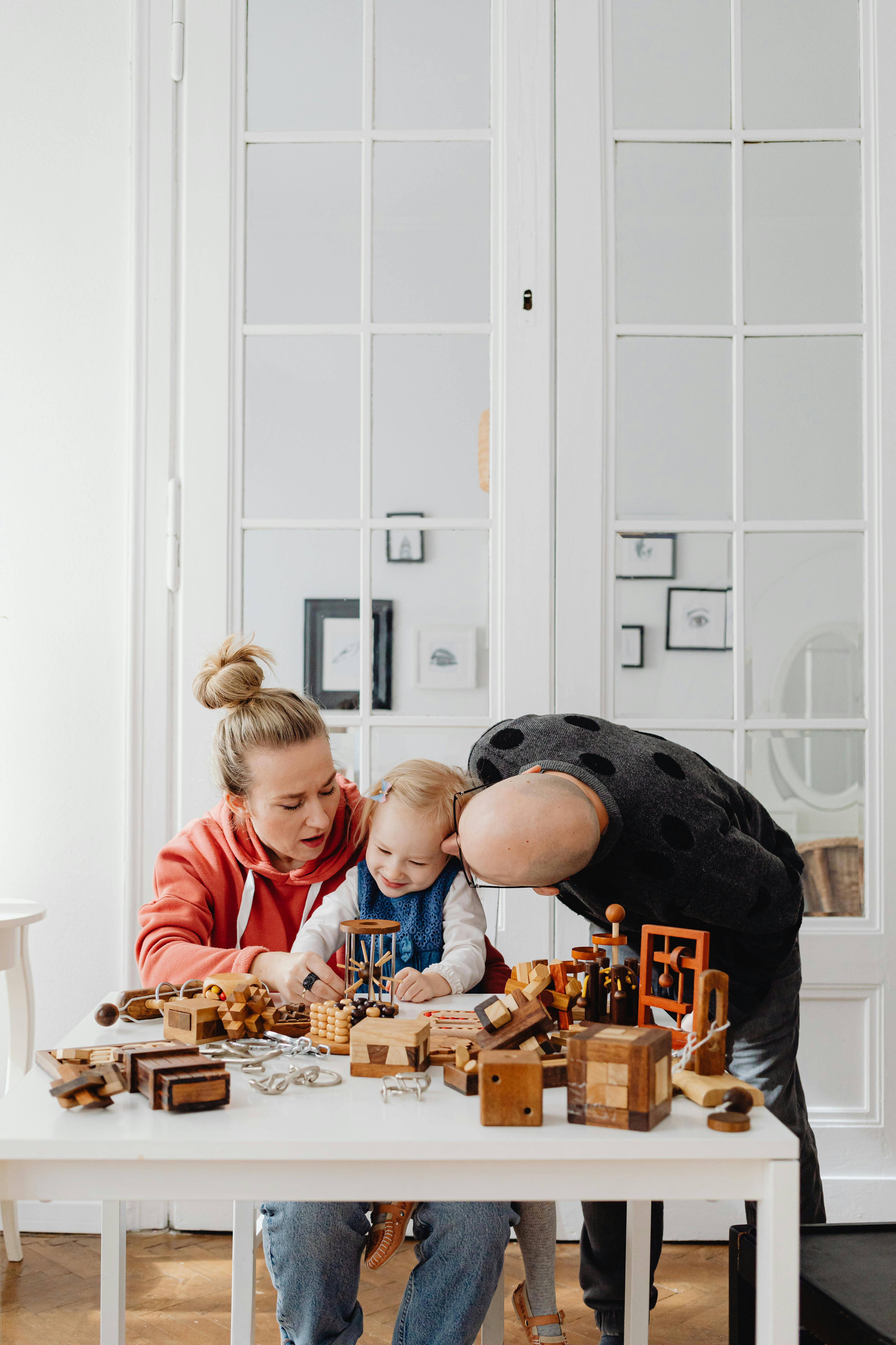 man and woman with their child playing with wooden toys