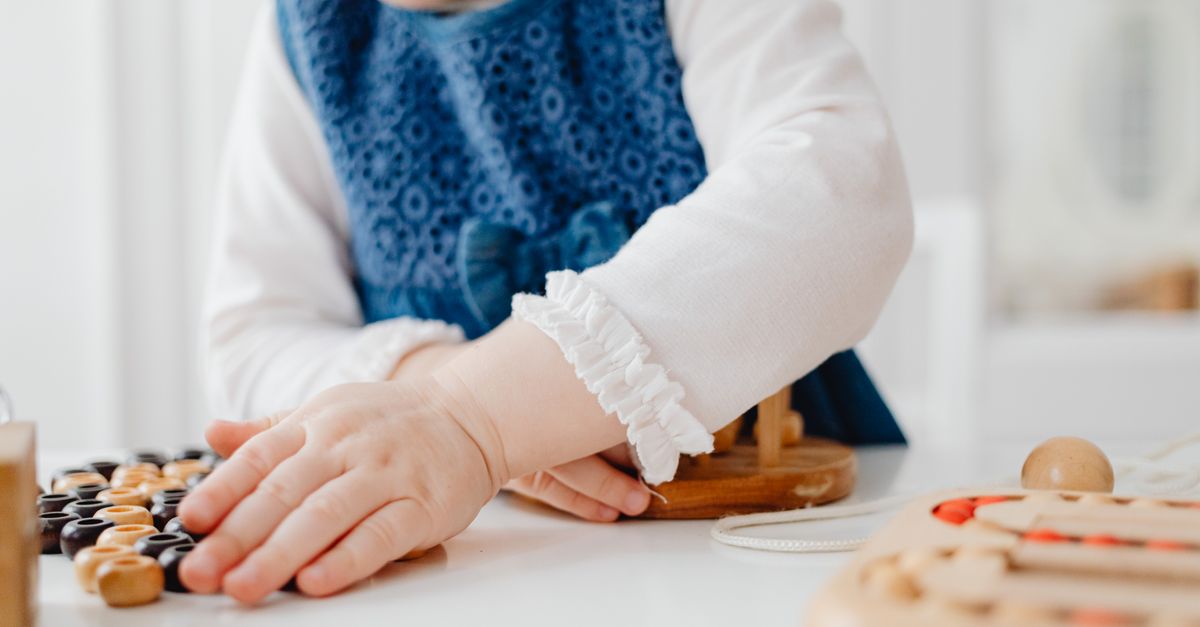 Un jeune enfant jouant avec des jouets éducatifs en bois à l'intérieur, favorisant la créativité et l'apprentissage.