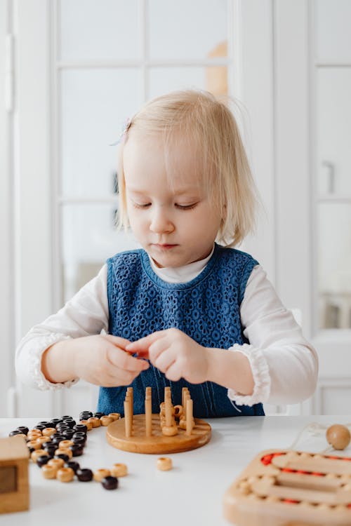 A Young Girl Playing Wooden Toys on the Table