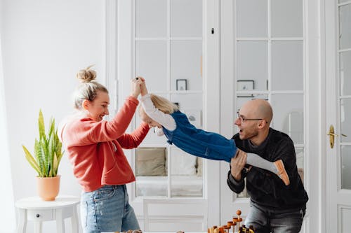 Free A Man and Woman Carrying their Daughter while Having Fun Stock Photo
