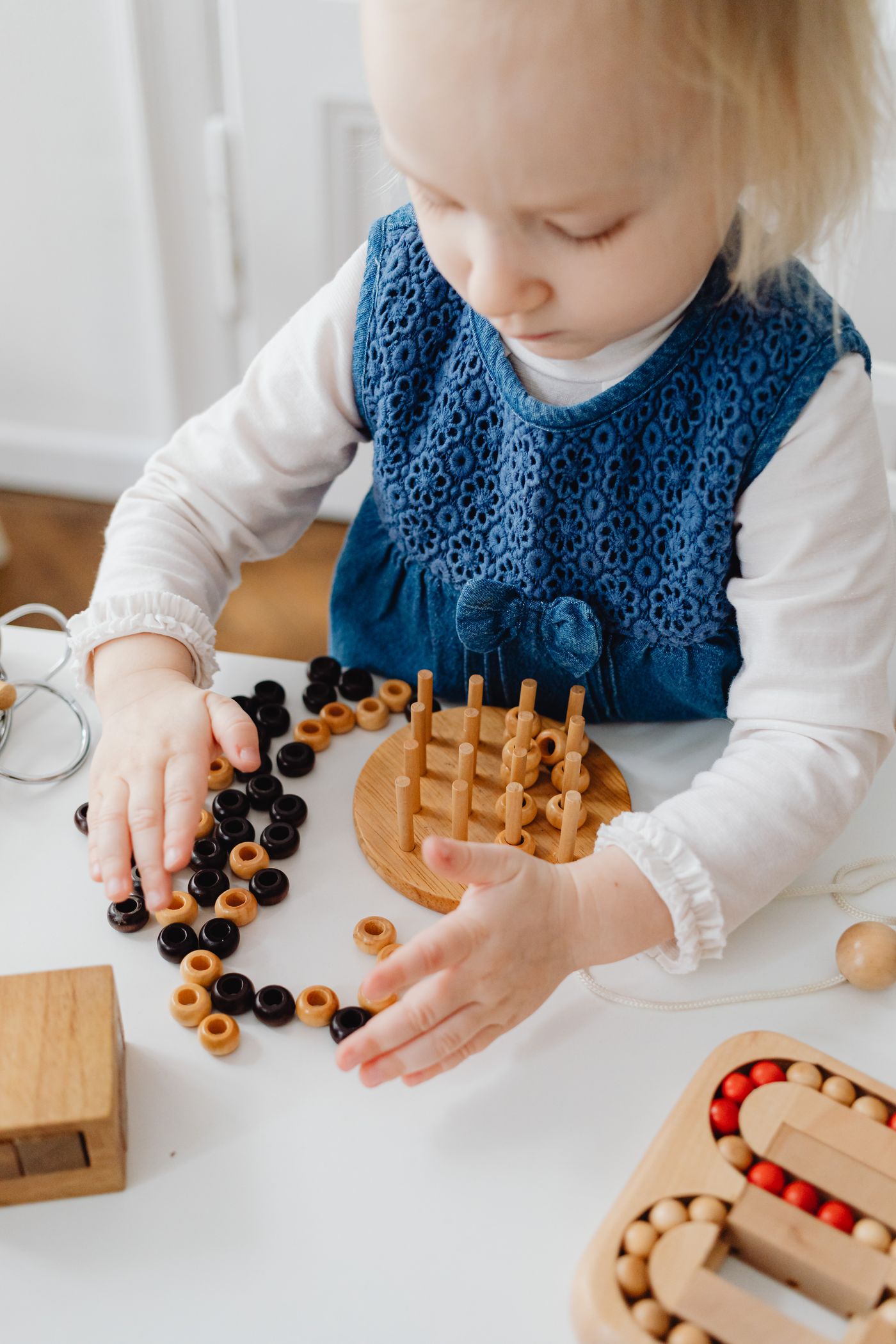 A child carefully handling wooden beads and educational toys during focused fine motor play