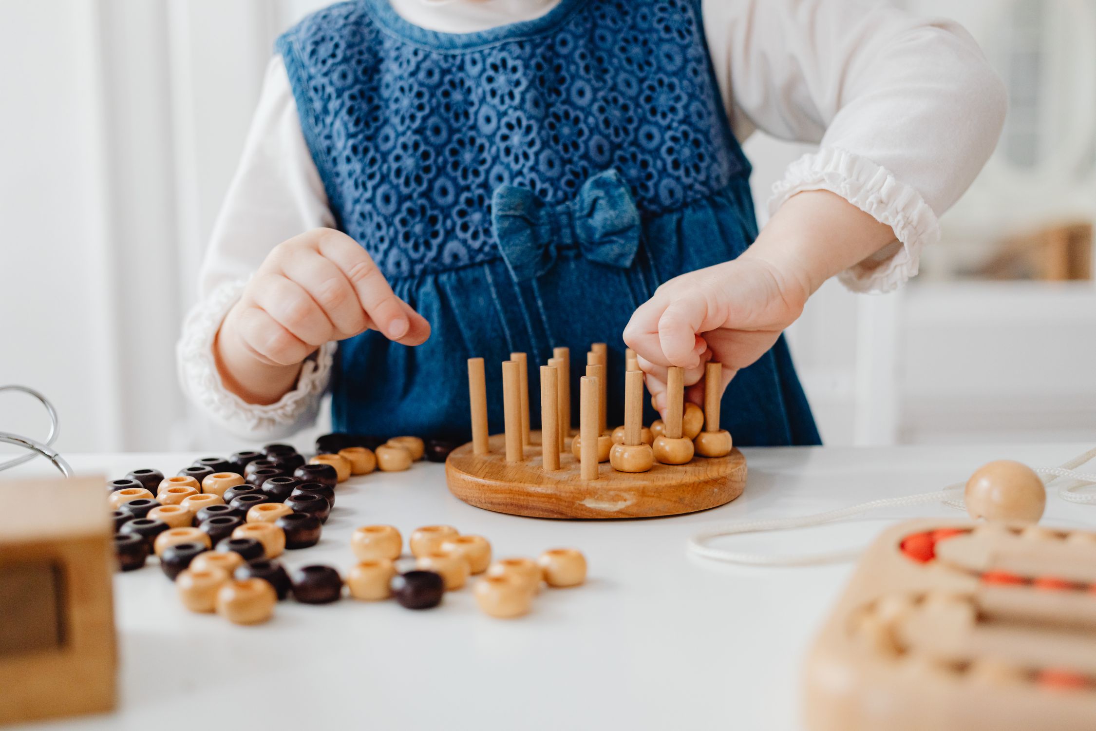 Mains d'un enfant manipulant un jeu en bois, une activité typique des matériels Montessori DIY pour la motricité fine.