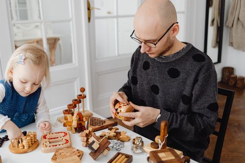 Free A father and daughter enjoying a playful time with wooden puzzles at home, fostering creativity and bonding. Stock Photo