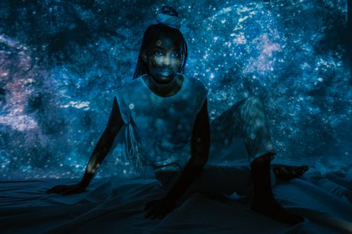 Free Creative portrait of a woman with cosmic projection background in low lighting. Stock Photo