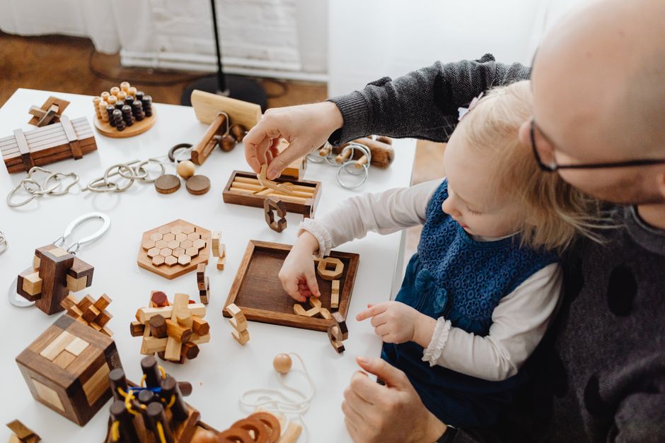 Father and child enjoy bonding time with various wooden puzzles and educational games.