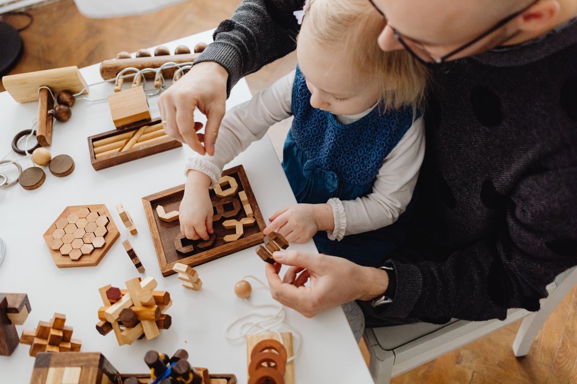 Father guiding his daughter while using educational toys