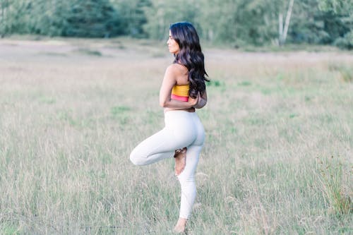 A Woman Doing Yoga on the Middle of a Grass Field