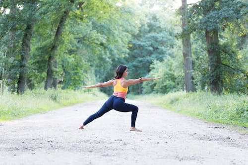 Free A Woman in Black Leggings Stretching Her Body while Standing on the Road Stock Photo