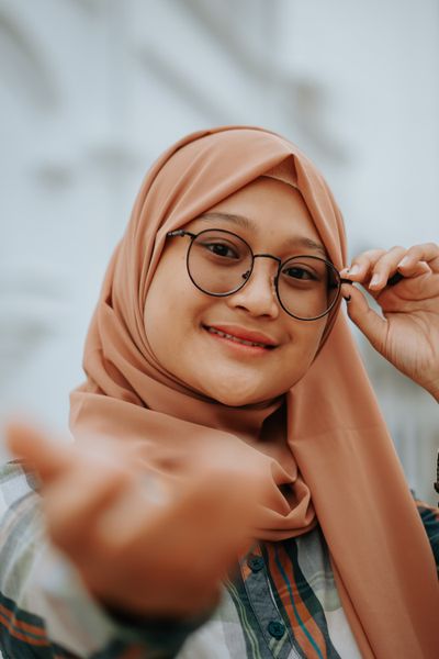 Ibu muda berkaca mata bertudung tersenyum