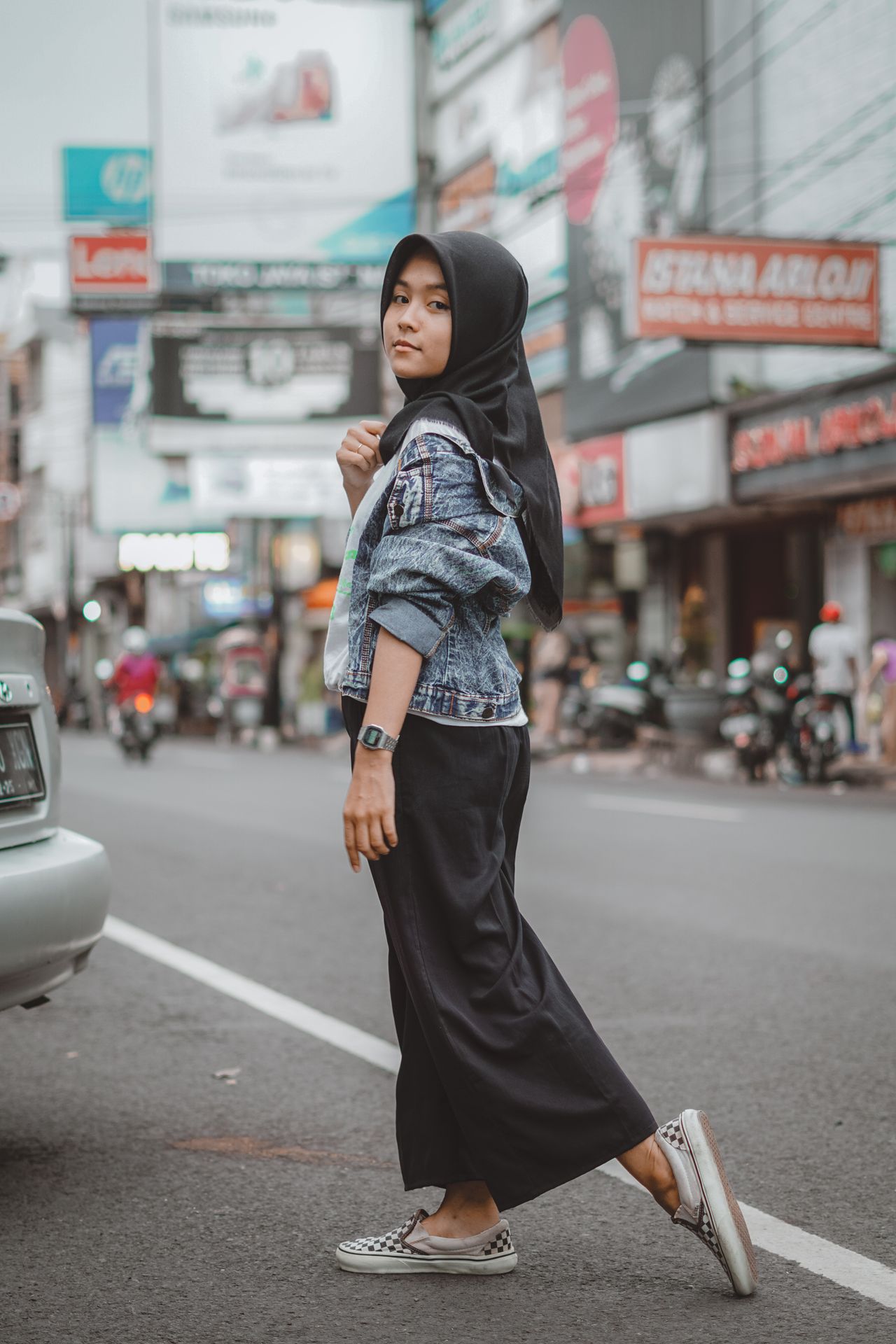 Woman in a denim jacket and black wide-leg pants on a city street