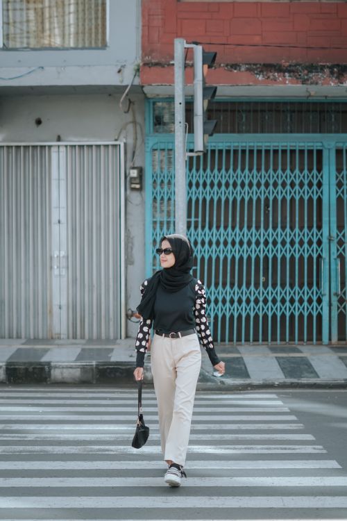 Free Stylish young woman wearing sunglasses and headscarf crossing a city street on a zebra crossing. Stock Photo