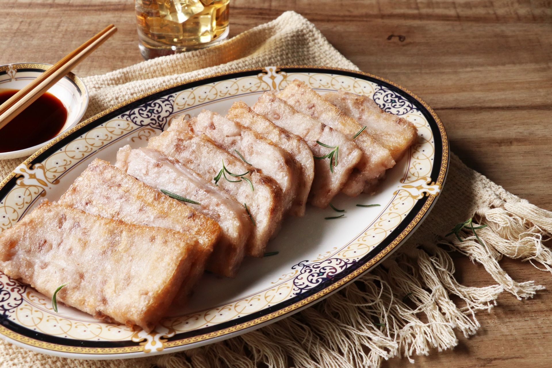 Delicious fried taro slices garnished with herbs served on a decorative plate with dipping sauce.