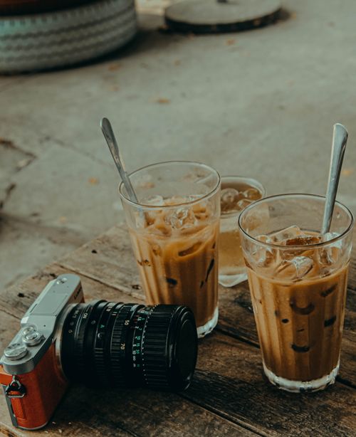 Free Two iced coffee glasses with camera on rustic table, perfect for beverage lifestyle themes. Stock Photo