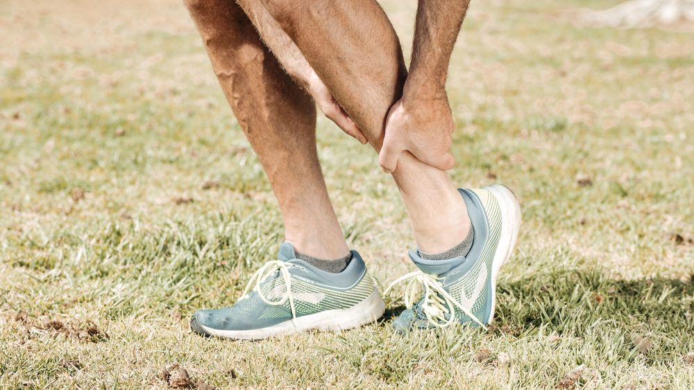 Runner holding calf and lower leg outdoors