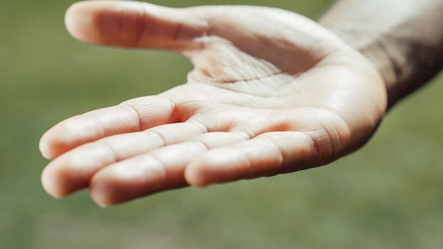 Close-up of an open hand with outstretched palm against a blurred green background