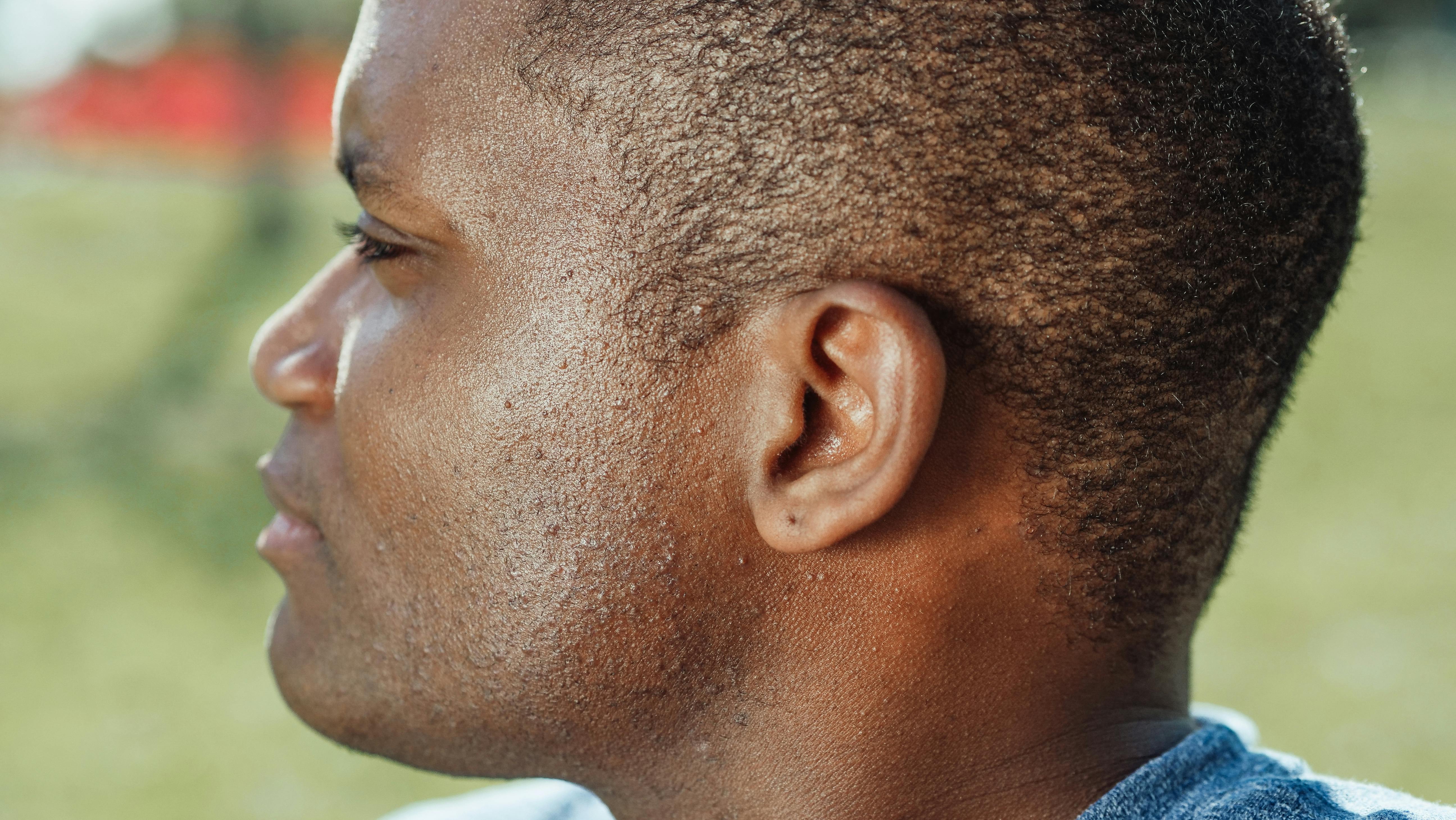 Extreme close-up side profile of a man outdoors with soft focus on the skin.