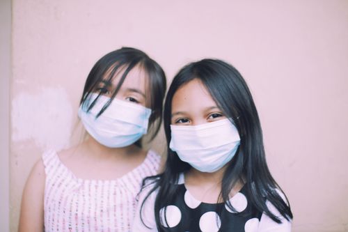 Free Two young girls wearing face masks for protection during the pandemic. Stock Photo