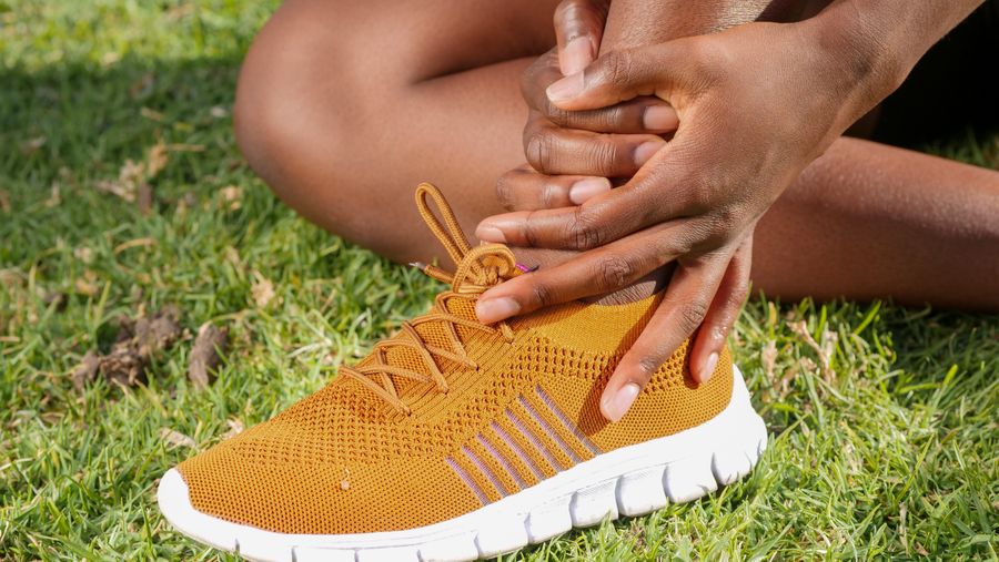 Deportista sujetando el pie tras una molestia durante actividad física