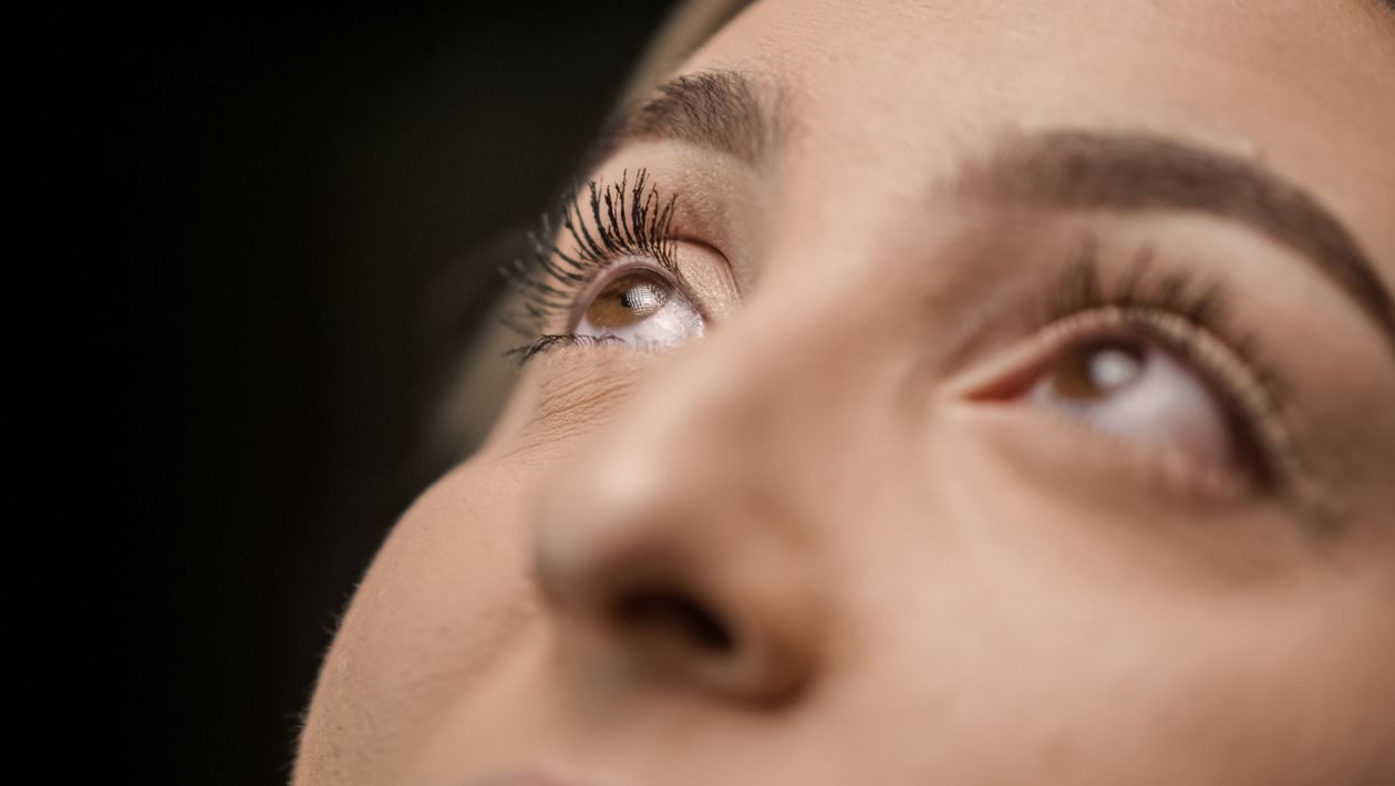 Close-up of a woman's eyes gazing upward, emphasising the upper eyelids and eyelashes — the area addressed by upper blepharoplasty