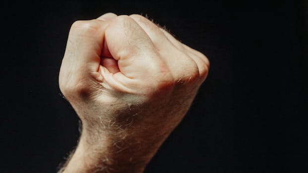 Detailed close-up of a clenched human fist against a dark background, symbolizing strength and determination.