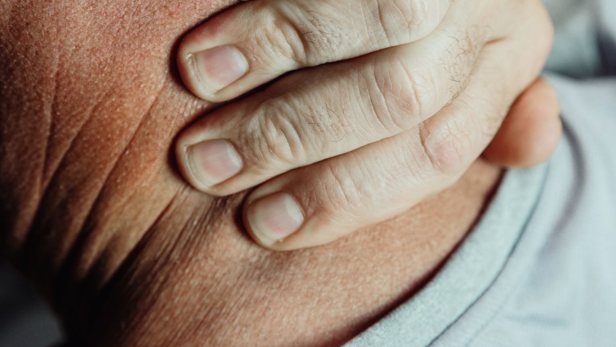 Person holding the back of their neck in discomfort, illustrating chronic neck pain