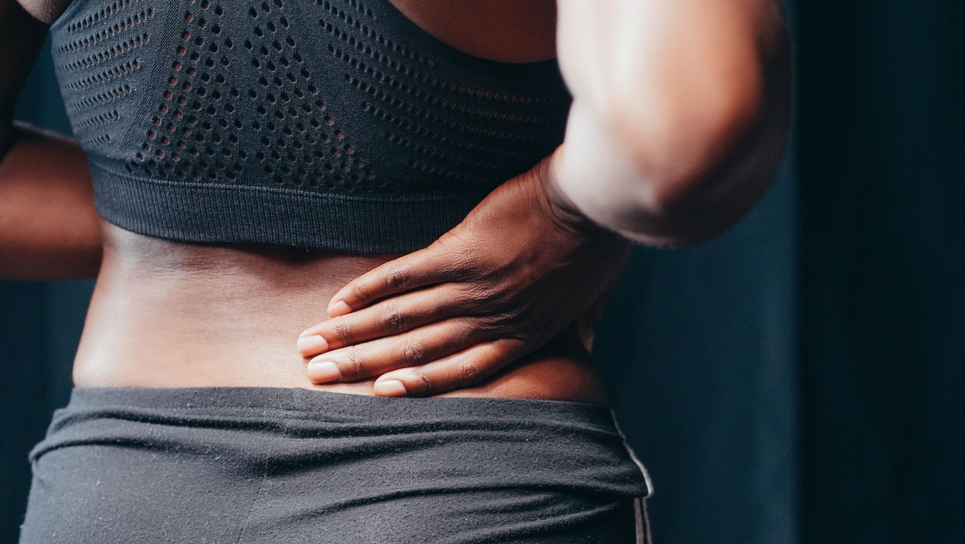 Person holding the lower back to show back pain before choosing support