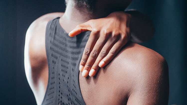 Man In Black Tank Top Holding His Back 