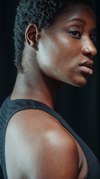 Side profile portrait of a woman with afro hair, looking pensive and serious indoors.