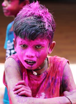 A young boy covered in pink powder during a lively Holi festival in Hyderabad, India.