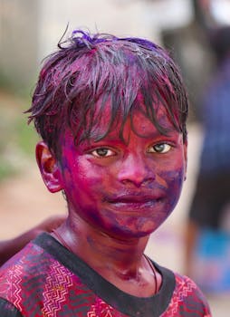 Smiling Indian boy with colorful face paint during Holi festival in Hyderabad.