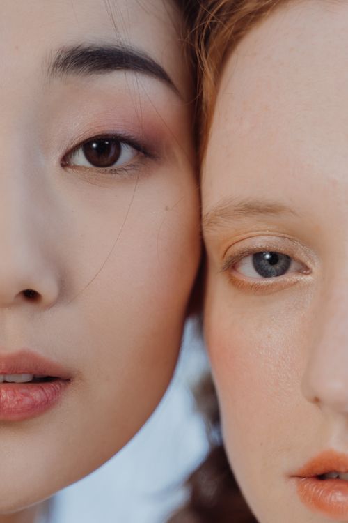 Free Artistic close-up of two women highlighting contrasting eye colors and features. Stock Photo