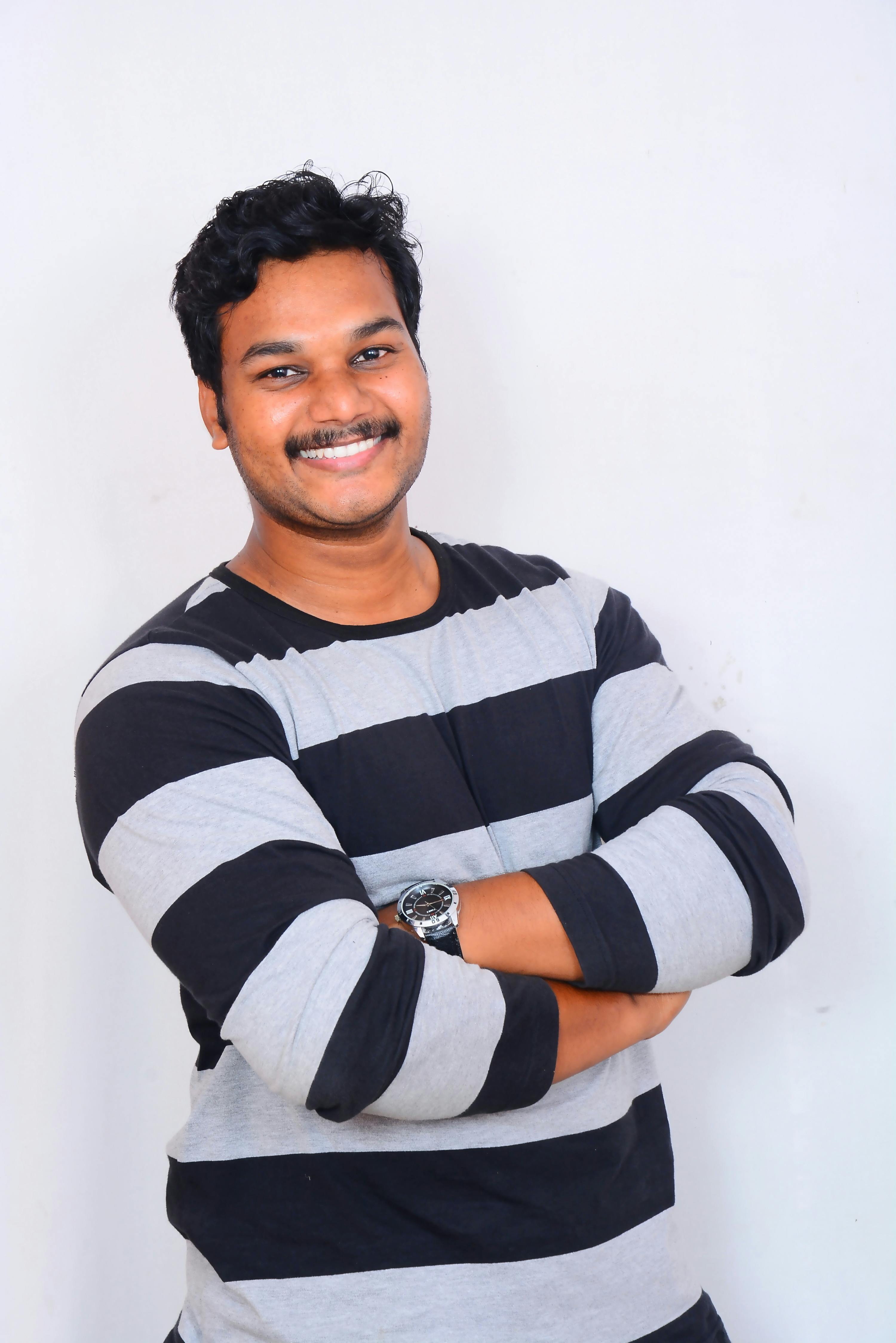 Portrait of a confident South Asian man smiling with arms crossed. Studio shot.