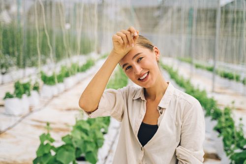 Free A joyful woman posing in a greenhouse surrounded by lush plants. Stock Photo