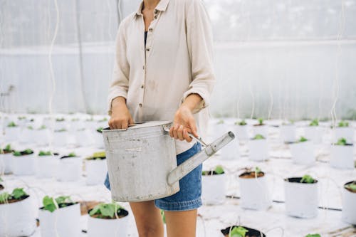 Woman Wearing White Top and Denim Shorts Holding a Watering Pot