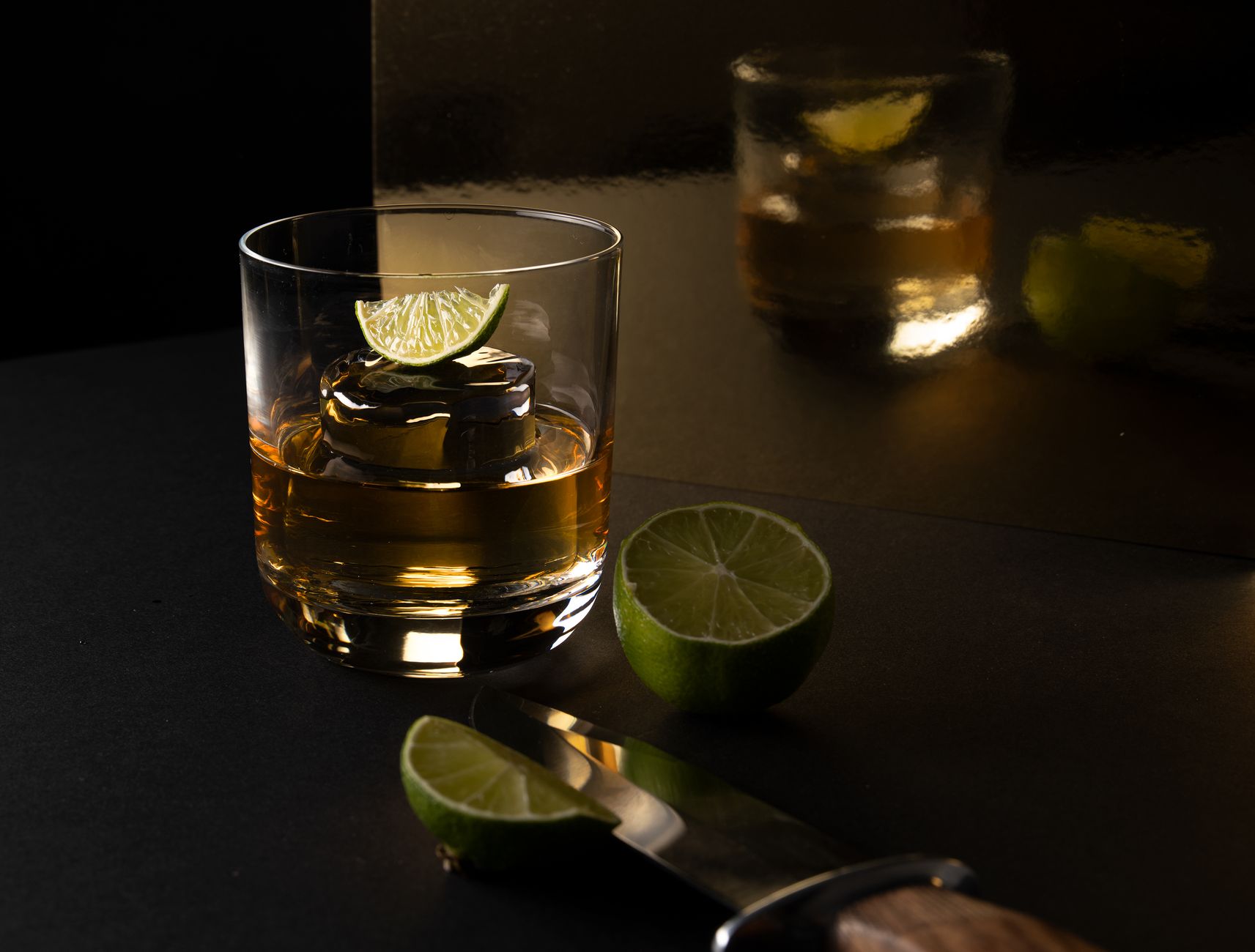 A crystal whisky glass with ice cubes reflecting soft light, showcasing the amber color of premium Japanese whisky.