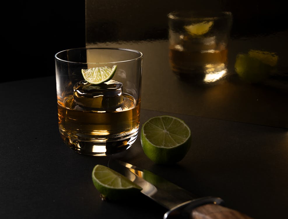 Clear Drinking Glass With Yellow Liquid and Sliced Lime