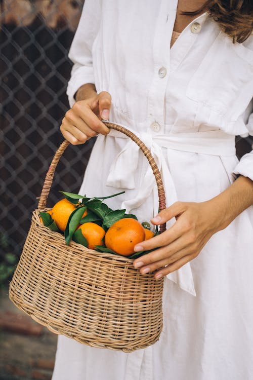 Person Holding Brown Woven Basket With Orange Fruits