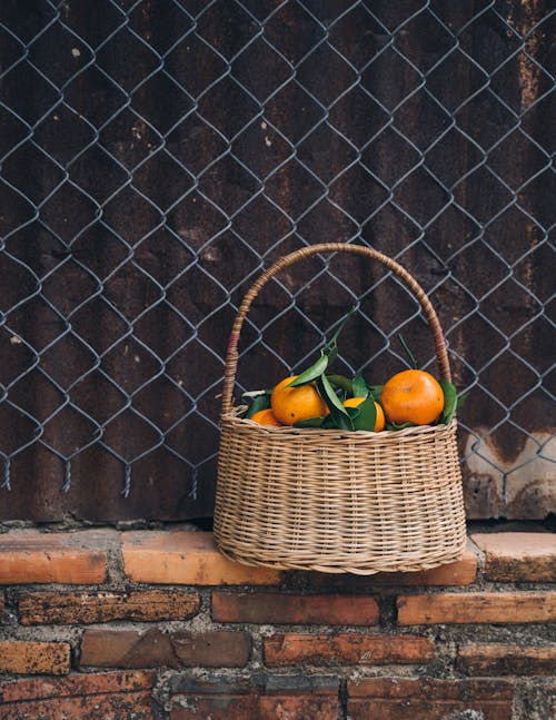Brown Woven Basket With Fruits on Brown Brick Wall