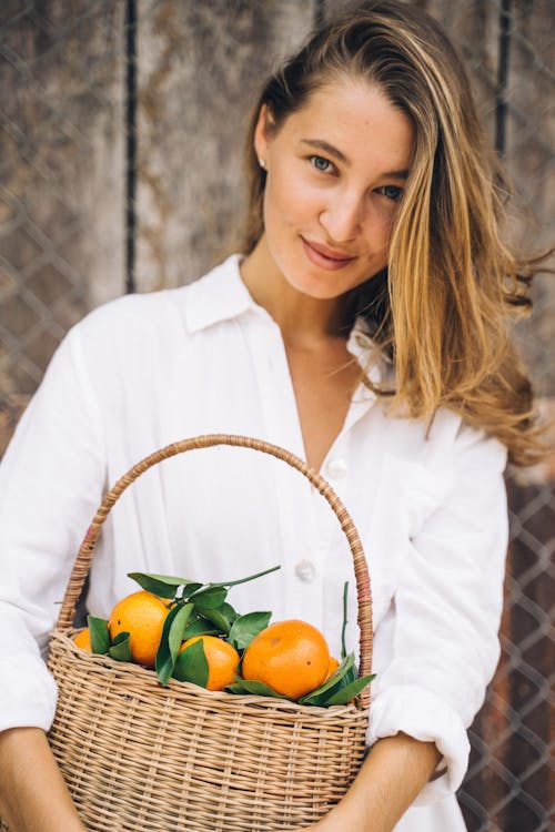Woman in White Dress Shirt Holding Basket of Fruits