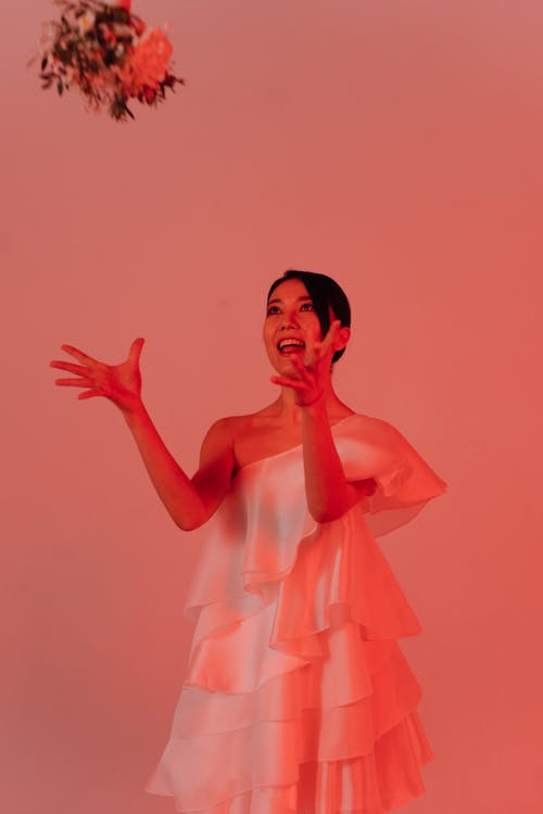 Woman in White Dress Standing and Throwing Bouquet of Flowers