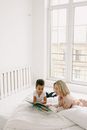 Mother and Son Reading Book Together while Lying on Bed