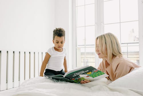 Kostenloses Stock Foto zu afroamerikanisches mädchen, bett, buch