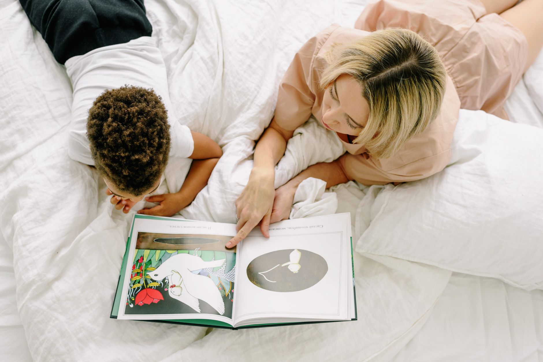 테슬라 취득세, 보험료, 충전비 총비용 계산 3 A mother and son enjoy quality time reading a book on a comfortable bed, promoting family bonds.