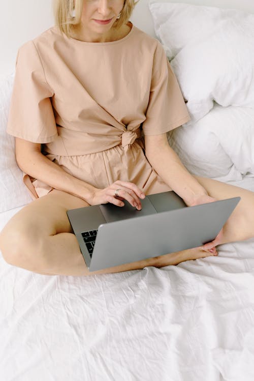 Woman Sitting on Bed while Using Laptop